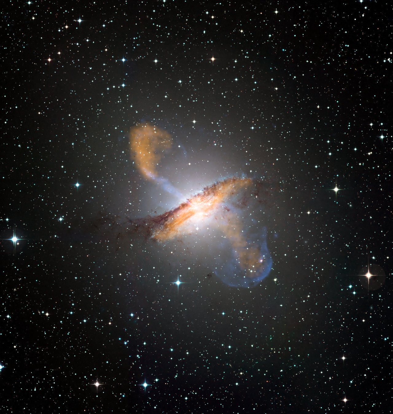 Colour composite image of Centaurus A, revealing the lobes and jets emanating from the active galaxy’s central black hole. This is a composite of images obtained with three instruments, operating at very different wavelengths. Credit: ESO/WFI (Optical); MPIfR/ESO/APEX/A.Weiss et al. (Submillimetre); NASA/CXC/CfA/R.Kraft et al. (X-ray)